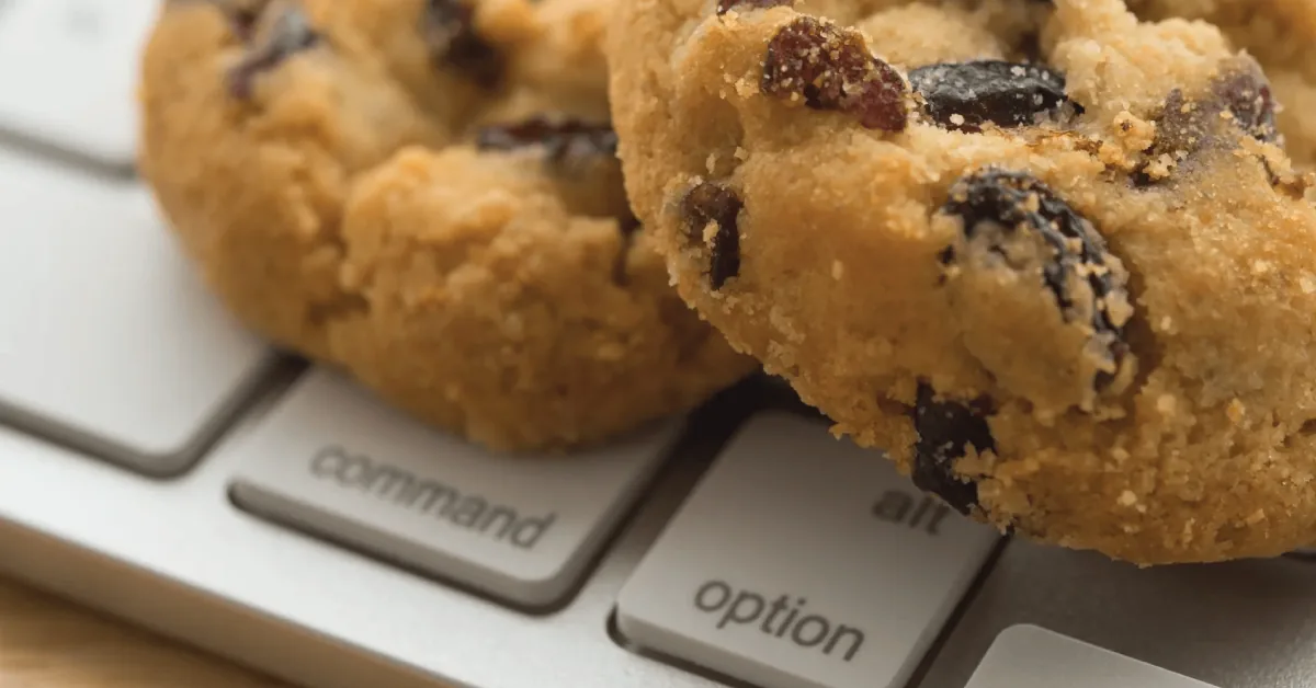 Two chocolate chip cookies resting on a laptop keyboard beside the Command and Option keys